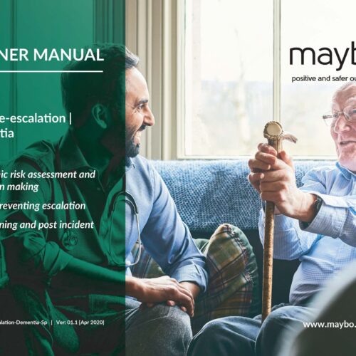 An elderly man holding a walking stick smiles as he interacts with a younger man sitting beside him on a sofa. A "TRAINER MANUAL" cover is superimposed on the left, featuring topics like "Safer de-escalation" and "Dementia". The Maybo logo, captioned "positive and safer outcomes," appears on the top right corner, with their website listed below.